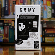 Trasera del juego Dany disponible en Mana House – Personalidades múltiples, Cartas ilustradas para comunicar ideas, Mecánica de roles ocultos, Juego psicológico, Estrategia y engaño.