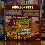 Trasera del juego 'Dungeon Petz' disponible en Mana House – Cuidado de criaturas, Limpieza de jaulas, Exposiciones monstruosas, Clientes exigentes, Decisiones tácticas con humor.