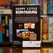 Vista trasera del juego de mesa 'Happy Little Dinosaurs' con detalles y componentes, en Mana House - Humor. Animales, Cartas, Dinosaurios, Humor, Prehistoria.