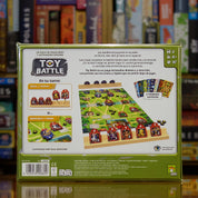 Trasera del juego 'Toy Battle' disponible en Mana House – Objetivo de capturar cuartel general o conseguir más medallas, Tropas con habilidades especiales, Escenarios como castillos, selvas y espacio, Duelo para todas las edades, Estrategia y diversión familiar.